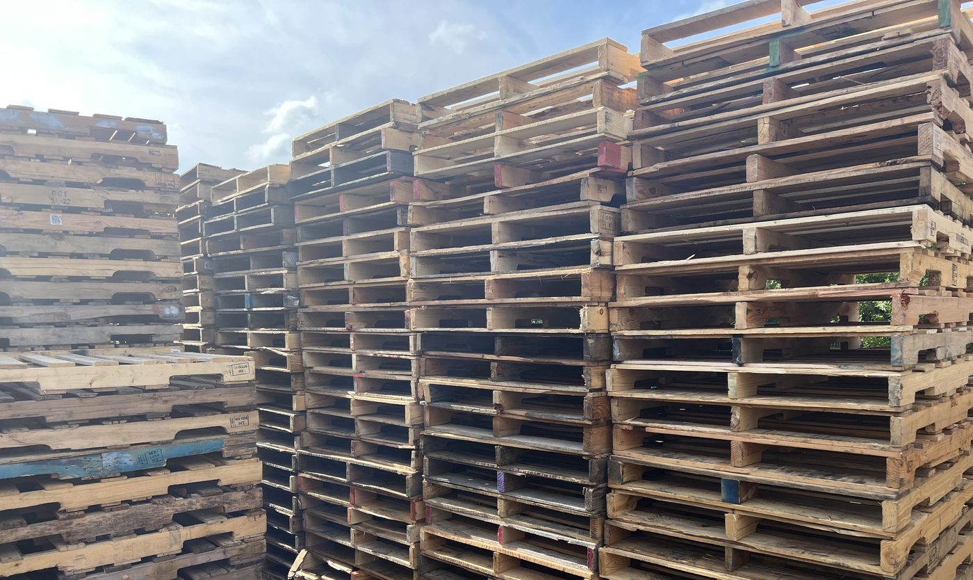 Mixed recycled wood pallets stacked outdoors at Florida pallet supplier yard